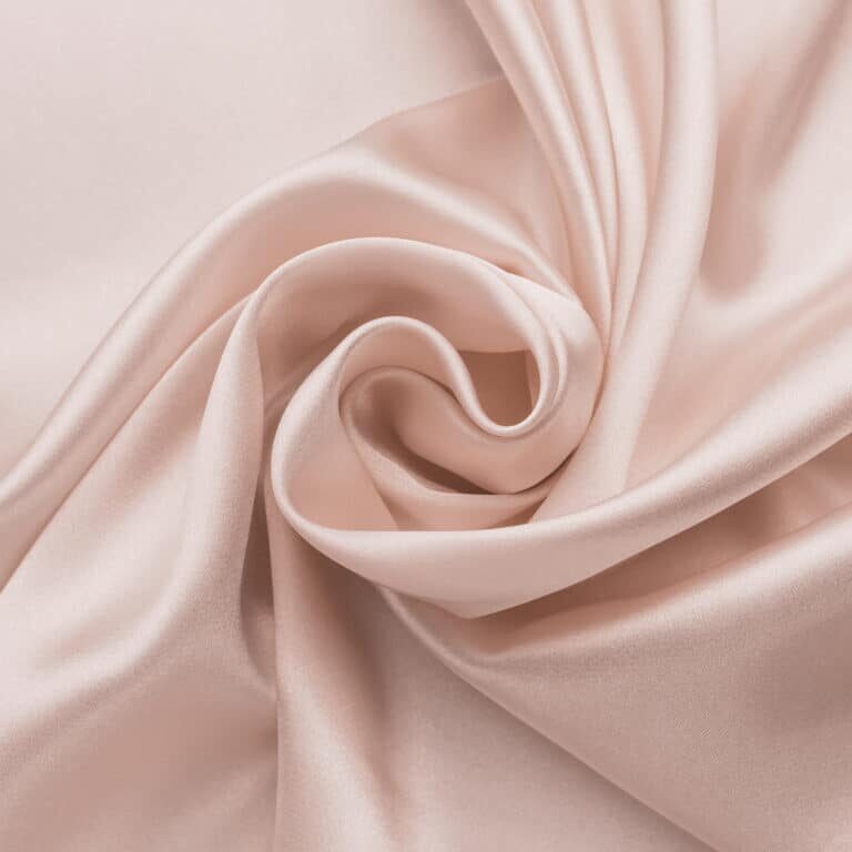 Abstract smooth silk background, folded satin texture. Beige fabric wallpaper. Pastel color pattern of wavy soft textile