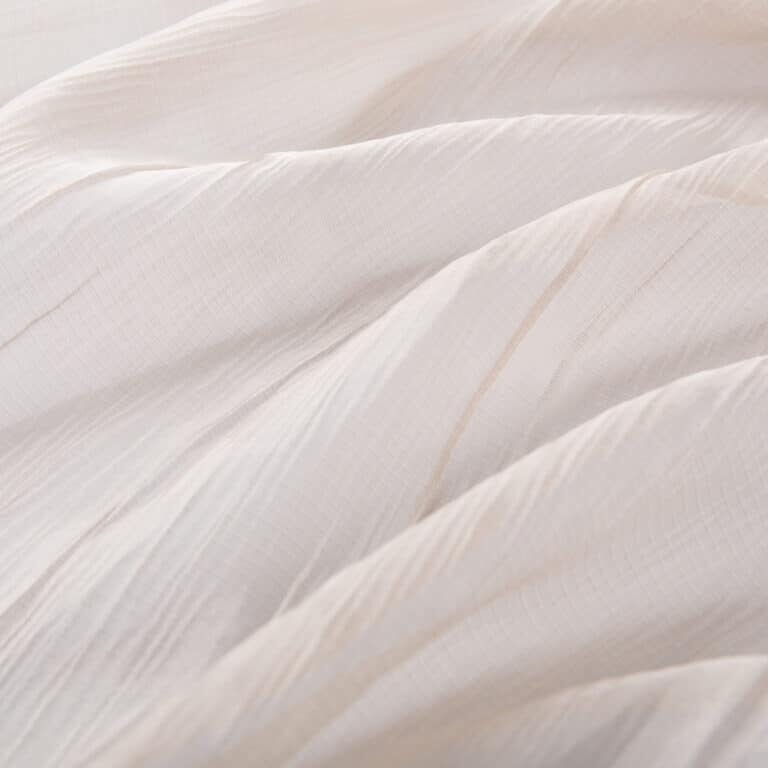 texture of beige translucent fabric with soft longitudinal folds, macro photography
