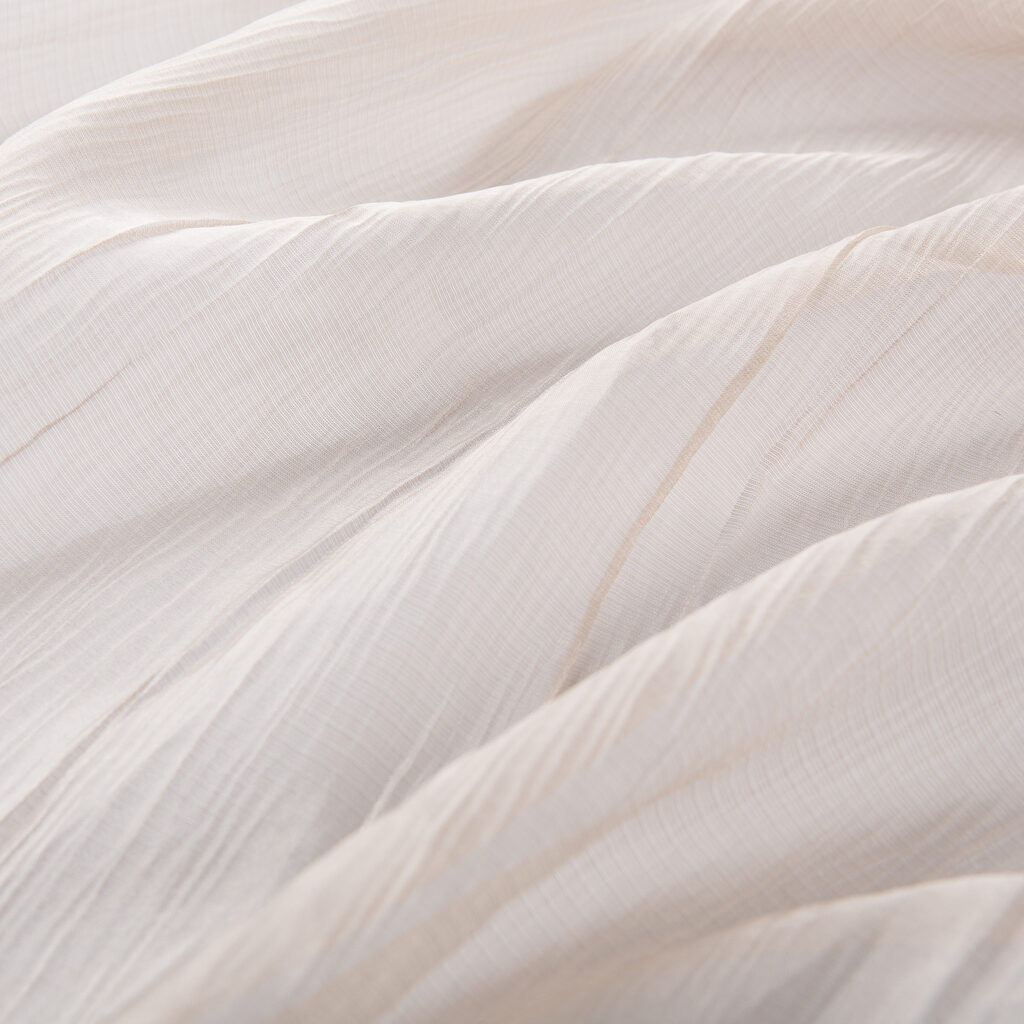 texture of beige translucent fabric with soft longitudinal folds, macro photography