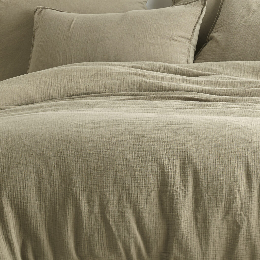 Comfortable bed with wooden frame with many pillows, blankets and sheets in the interior of a stylish bedroom