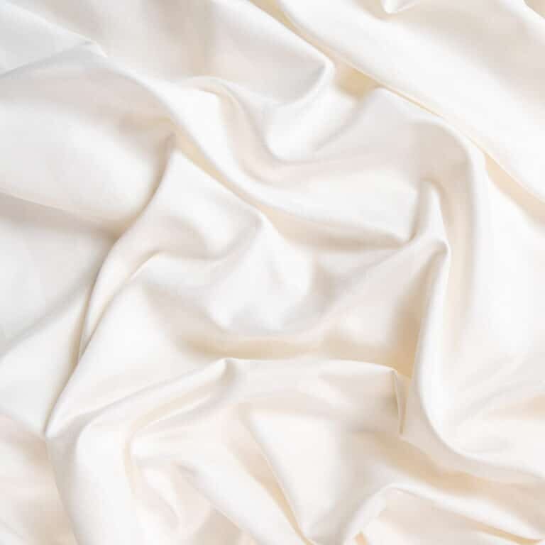 Waves and patterns of crumpled natural satin white milk color fabric