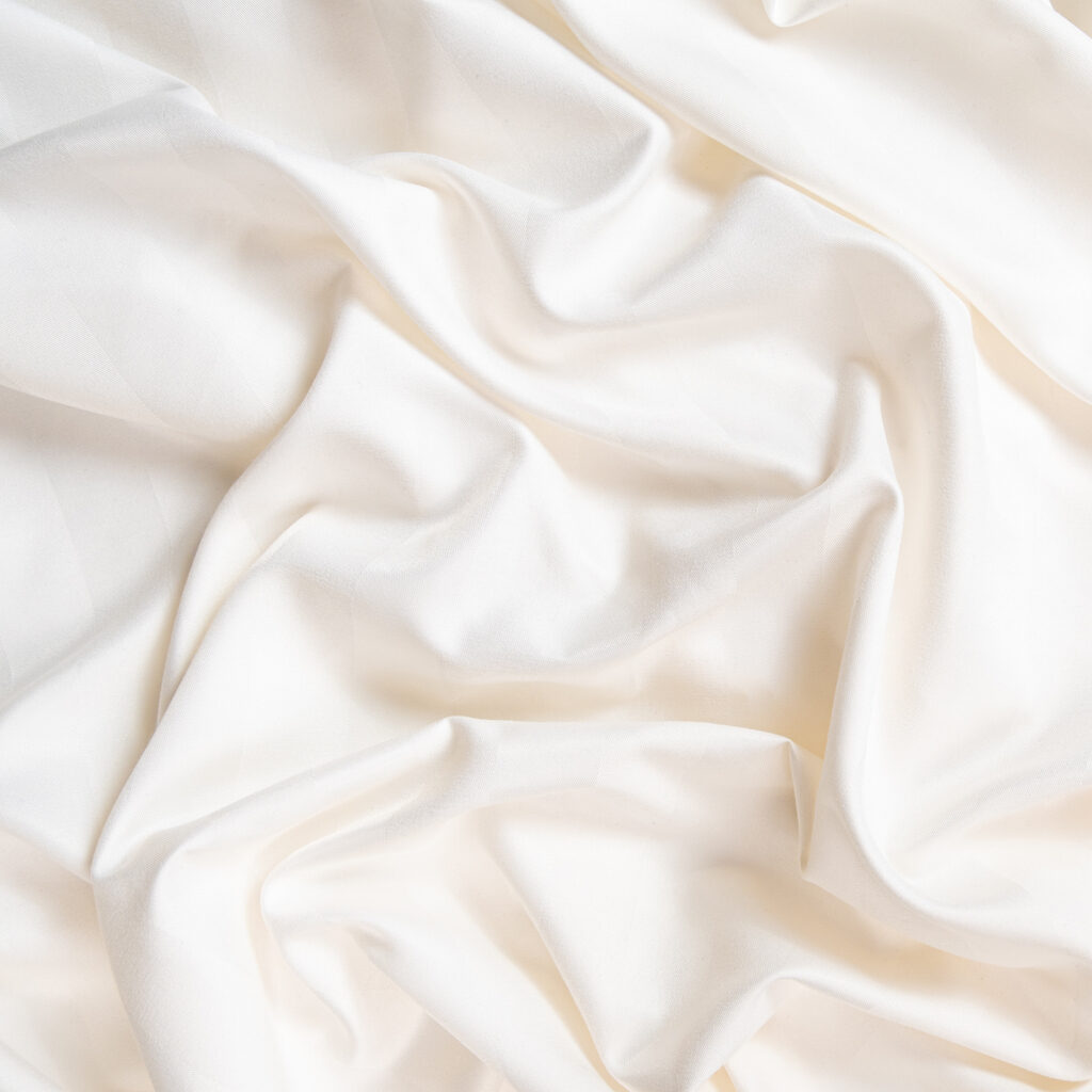 Waves and patterns of crumpled natural satin white milk color fabric