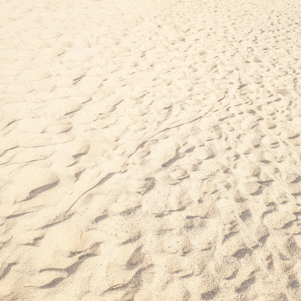 Summer beach sand background with natural wave pattern. Sand texture. Sunny gold sandy beach wallpaper