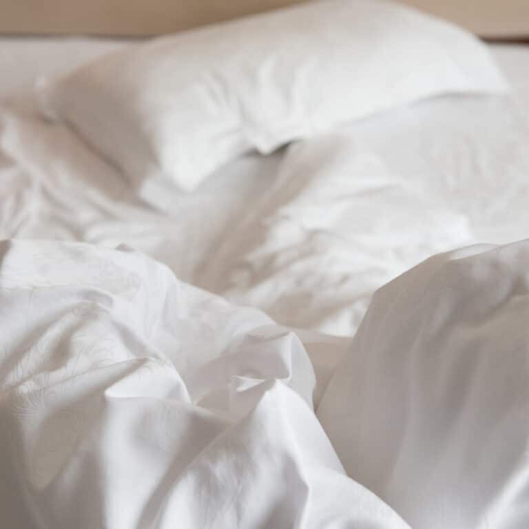 bed in a hotel room with unfolded quilt in the morning